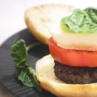 Caprese Burger featuring hamburger topped with tomato, fresh mozzarella, and basil