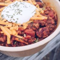 Haute Chili. Yummm. 3 Photo of chili topped with cheddar cheese and sour cream overlooking fall vibes.