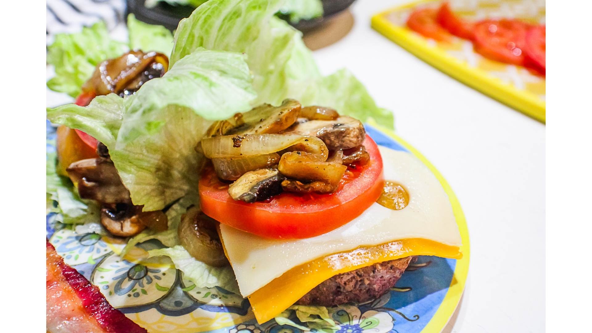 Cheyenne Cowboy Burger (Authentic Wyoming Recipe) 8 cowboy burger lettuce wrap with hamburger, swiss, cheddar, tomato and caramelized onions and mushrooms visible on top of a lettuce wrap